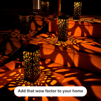 Several tall black metal lanterns with intricate cutout patterns are placed on outdoor stone steps, casting dramatic orange and red shadow patterns across the surface. A white rounded text bubble at the bottom reads, 'Add that wow factor to your home'.
